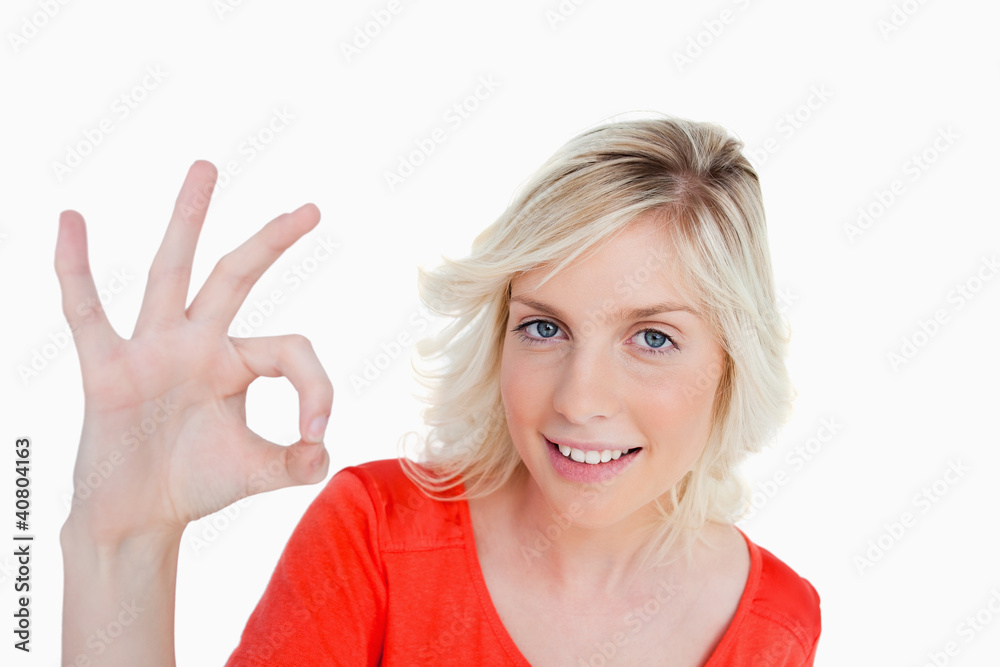 Smiling woman showing the OK sign while looking straight at the Smiling woman showing the OK sign while looking straight at the
