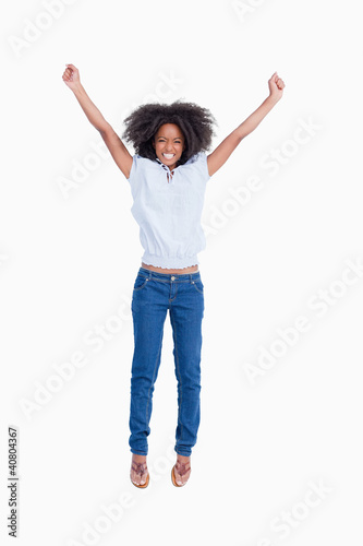 Young woman beaming while raising her arms above the head