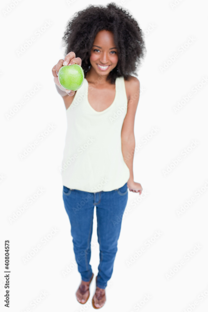 Relaxed young woman holding a green apple in front of her Relaxed young woman holding a green apple in front of her