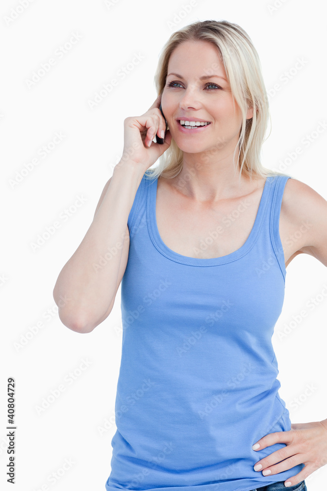 Smiling blonde woman using a mobile phone with a hand on her hip Smiling blonde woman using a mobile phone with a hand on her hip