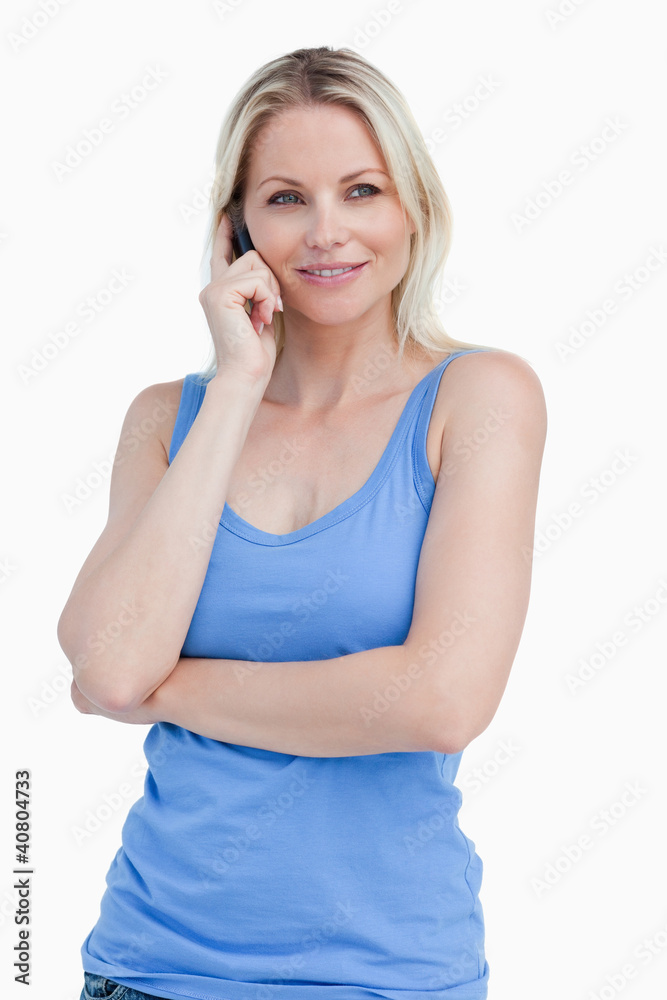 Blonde woman using a cellphone while standing with herarms cross Blonde woman using a cellphone while standing with herarms cross
