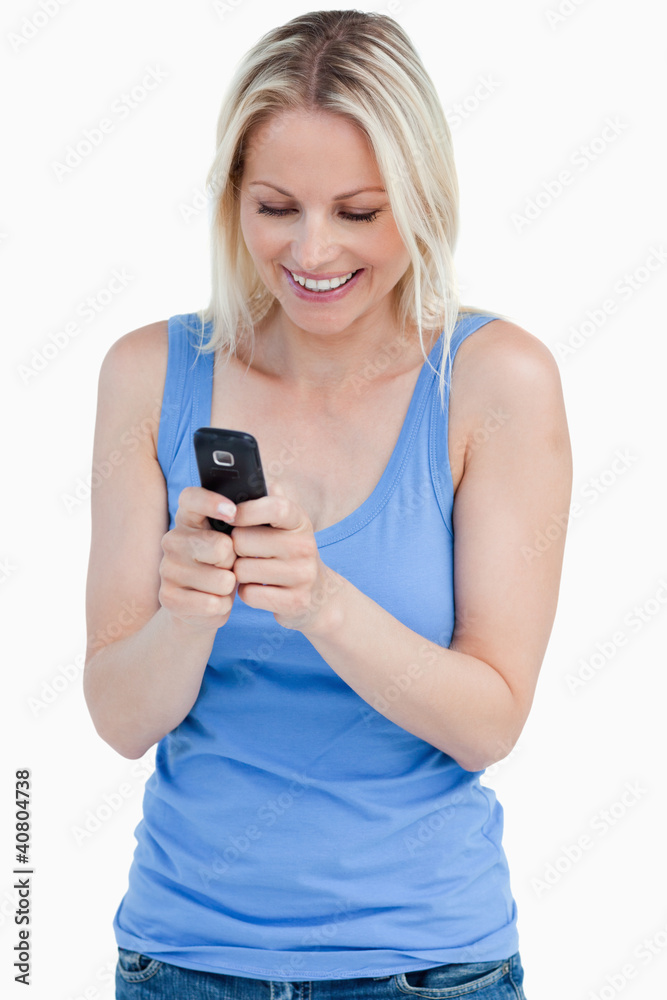 Smiling blonde woman sending a text with her cellphone Smiling blonde woman sending a text with her cellphone
