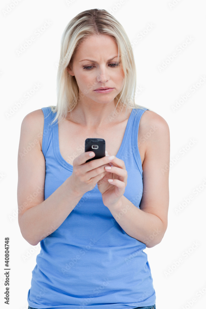Serious woman looking at her mobile phone while concentrating Serious woman looking at her mobile phone while concentrating