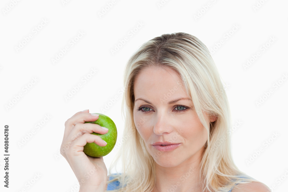 Thoughtful blonde woman holding a green apple Thoughtful blonde woman holding a green apple