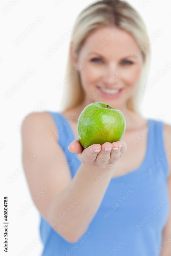 Delicious green apple held by a smiling blonde woman Delicious green apple held by a smiling blonde woman