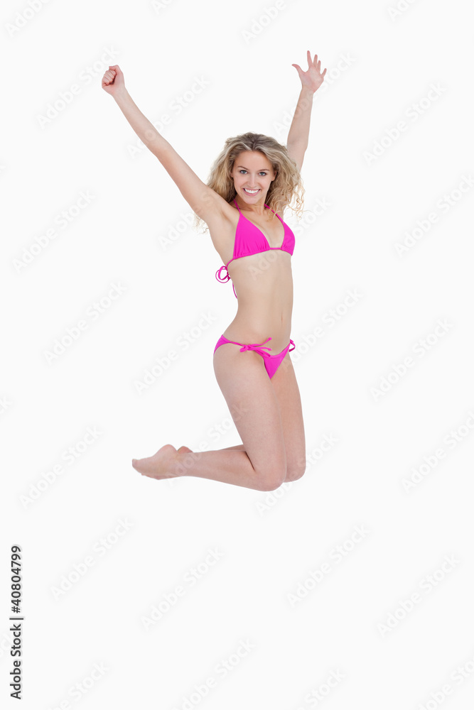Attractive blonde woman wearing a pink swimsuit while jumping Attractive blonde woman wearing a pink swimsuit while jumping