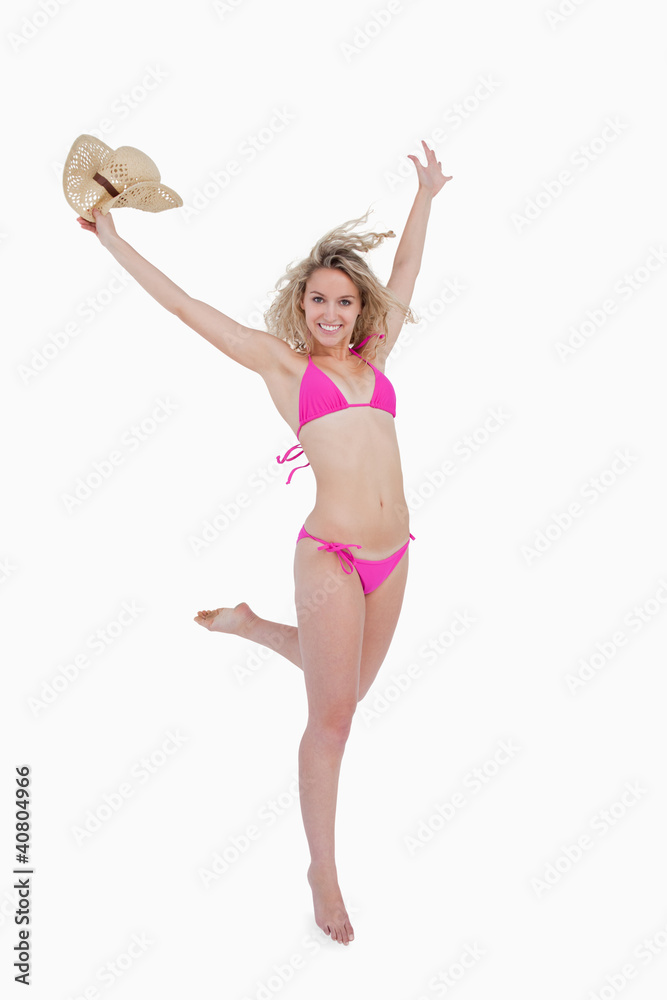 Smiling young blonde woman raising her arms while holding her ha