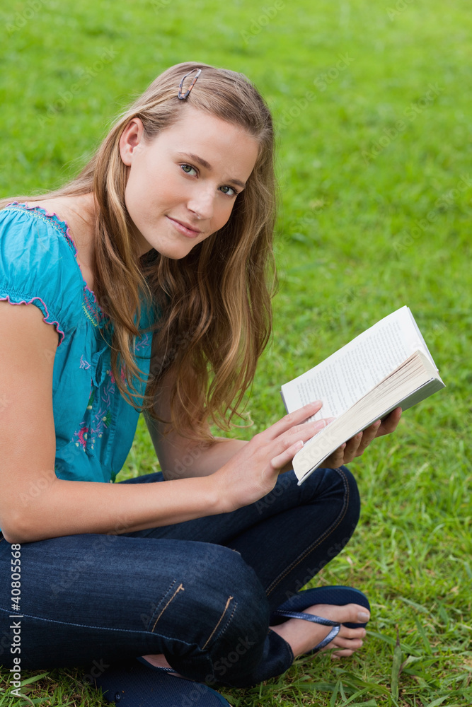 Obraz premium Young relaxed girl reading a book while sitting in the countrysi