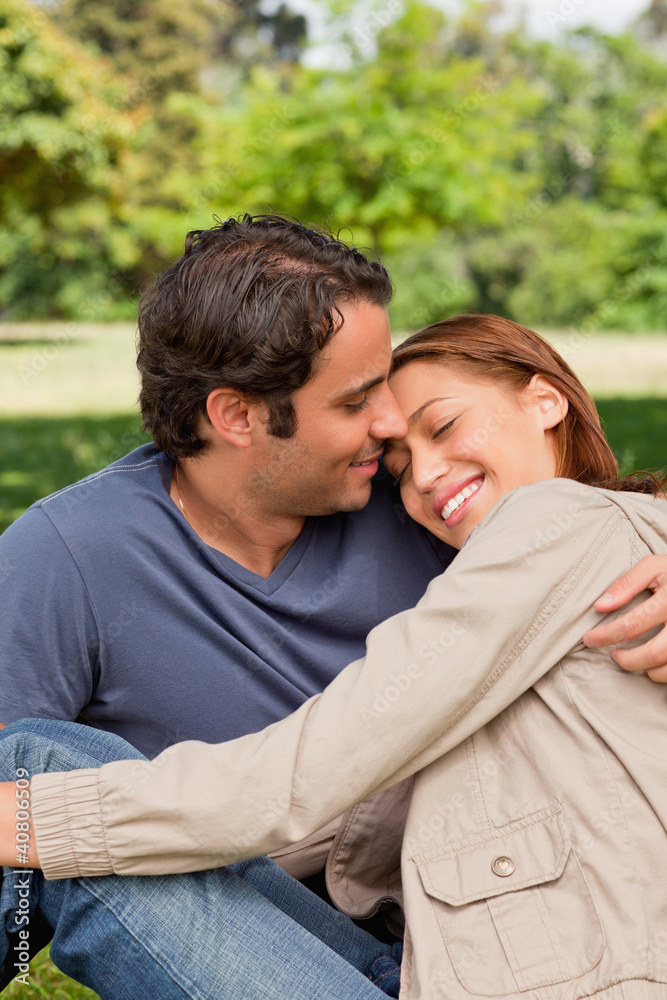 Man smiling as his friend rests her head on his shoulders