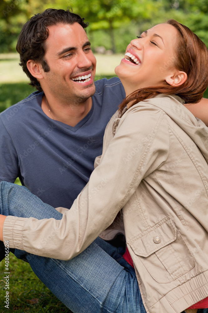 Two friends gleefully laughing as they are sitting next to each Two friends gleefully laughing as they are sitting next to each