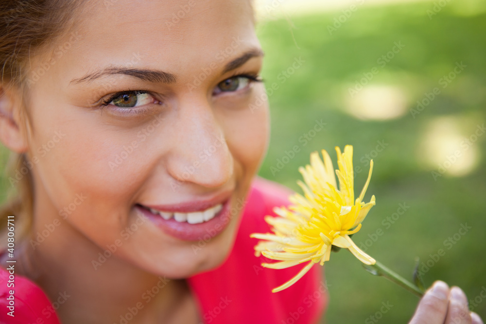 Woman smiling as she looks upwards while holding a yellow flower Woman smiling as she looks upwards while holding a yellow flower
