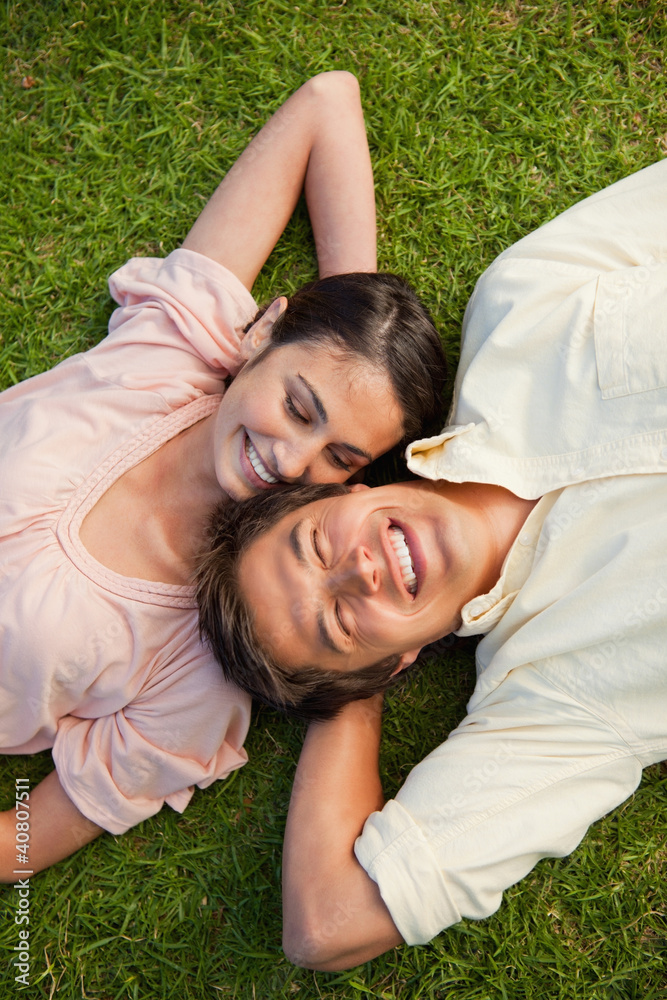 Woman looking at her friend while lying head to shoulder with hi Woman looking at her friend while lying head to shoulder with hi