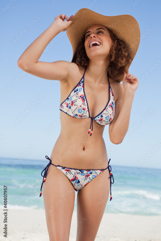 Young beautiful woman holding her hat while laughing