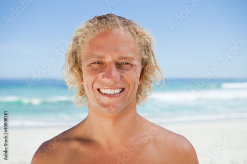 Young smiling man standing on the beach