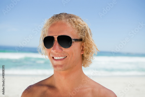 Smiling man wearing sunglasses while standing on the beach