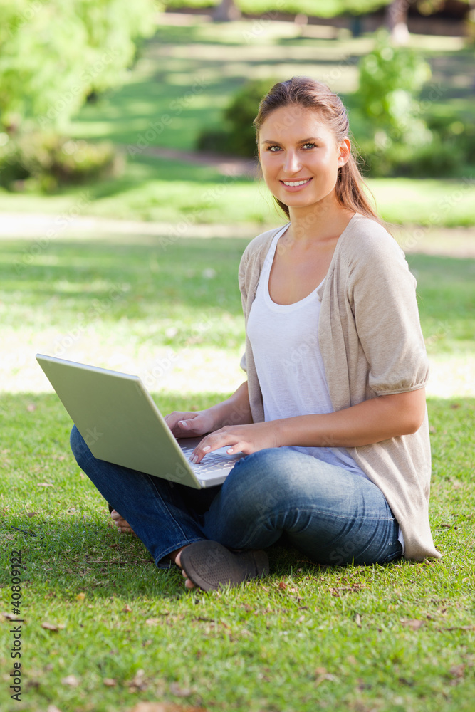 Smiling woman working on her notebook in the park Smiling woman working on her notebook in the park