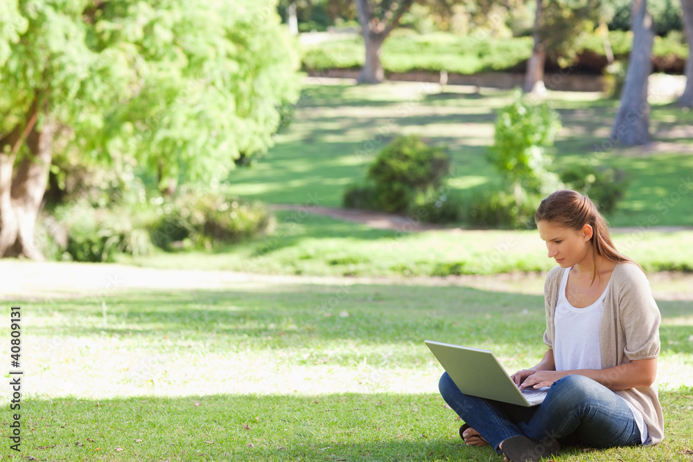 Woman sitting on the lawn working on her notebook