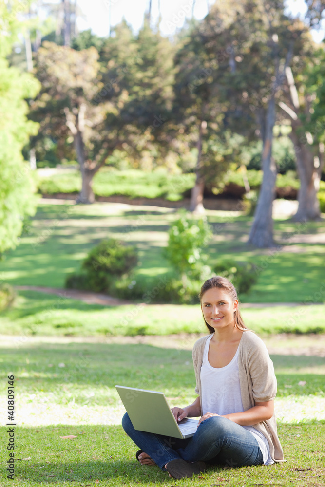 Smiling woman sitting on the lawn with her laptop Smiling woman sitting on the lawn with her laptop