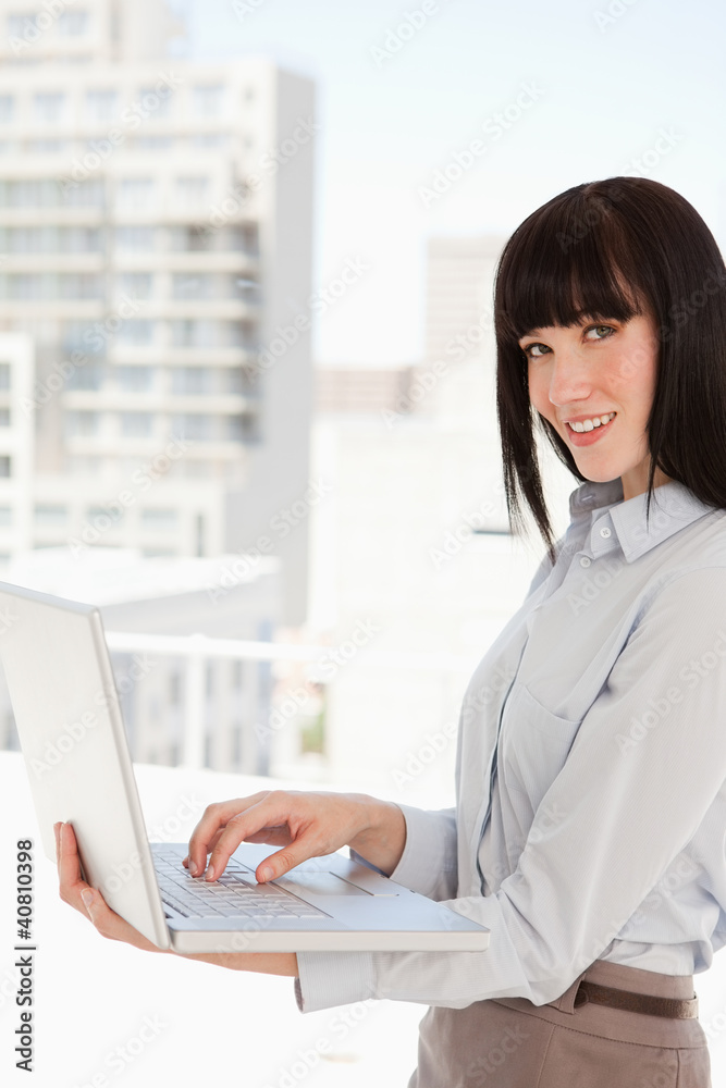 A woman looking at the camera while holding a laptop A woman looking at the camera while holding a laptop