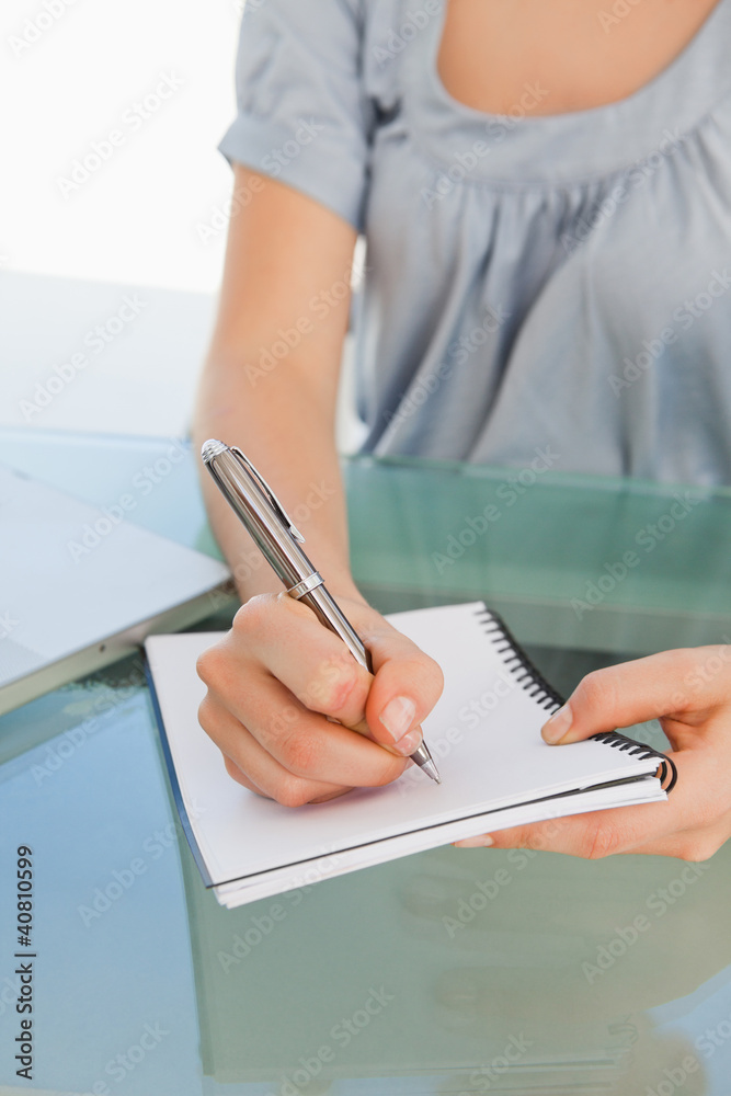 Fototapeta premium Close up of a woman writing on a notepad