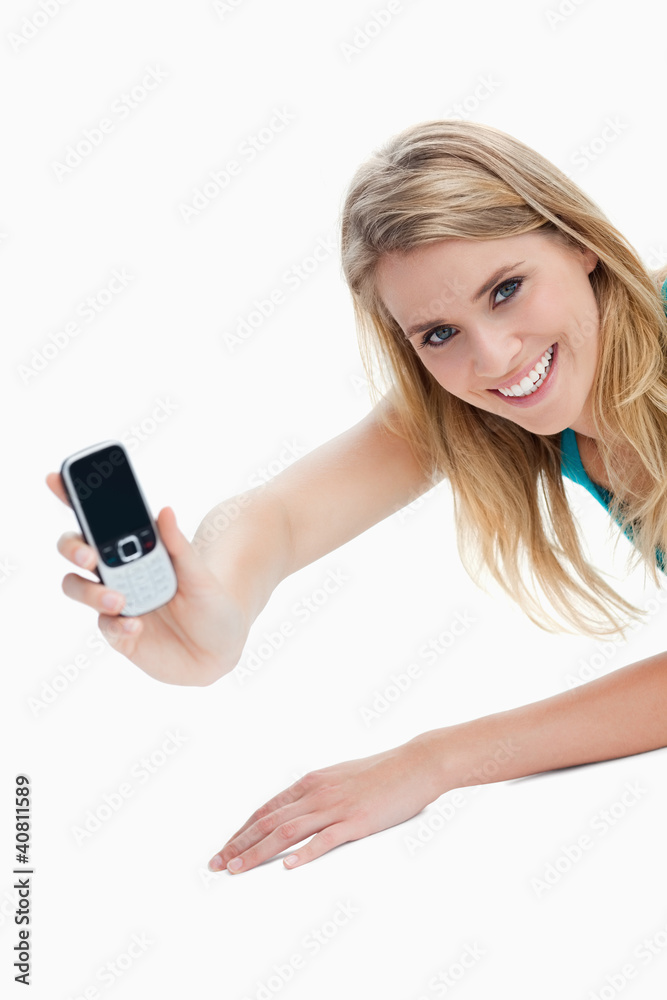 A young woman holding out her mobile phone is looking at the cam A young woman holding out her mobile phone is looking at the cam