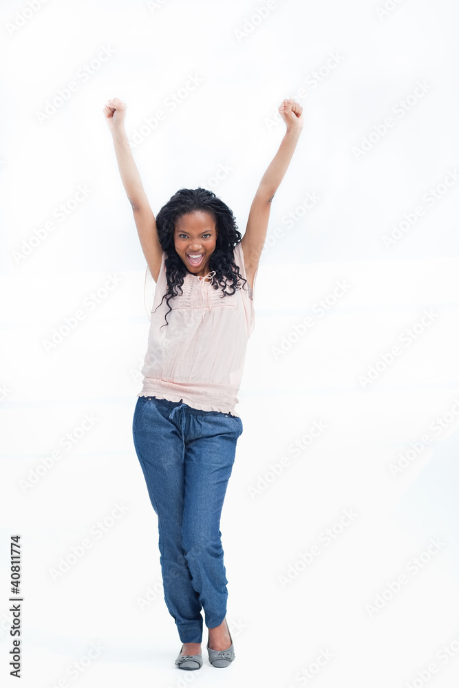 A young laughing woman stands with her arms held up in the air