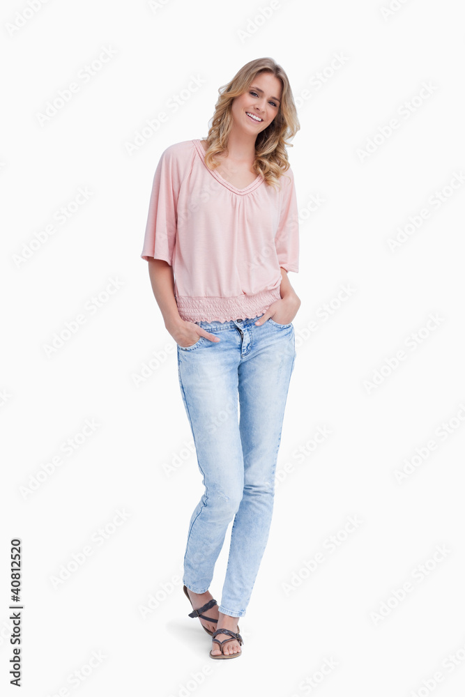 A smiling woman is standing with her hands in her pockets A smiling woman is standing with her hands in her pockets