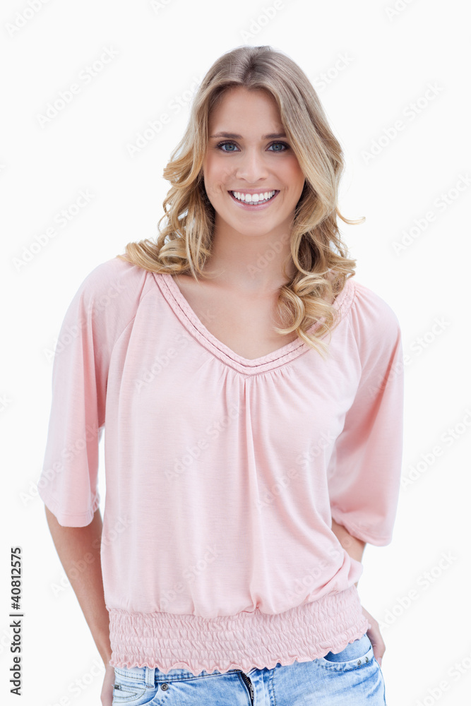 A smiling woman standing with her arms behind her back A smiling woman standing with her arms behind her back