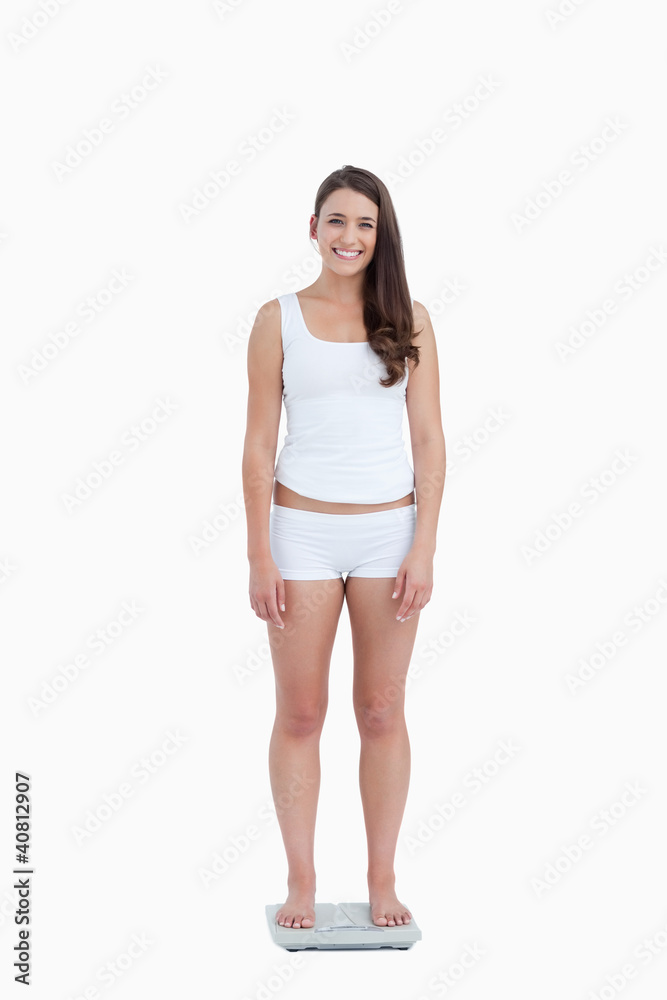 Smiling woman looking at the camera while standing on weighing s Smiling woman looking at the camera while standing on weighing s