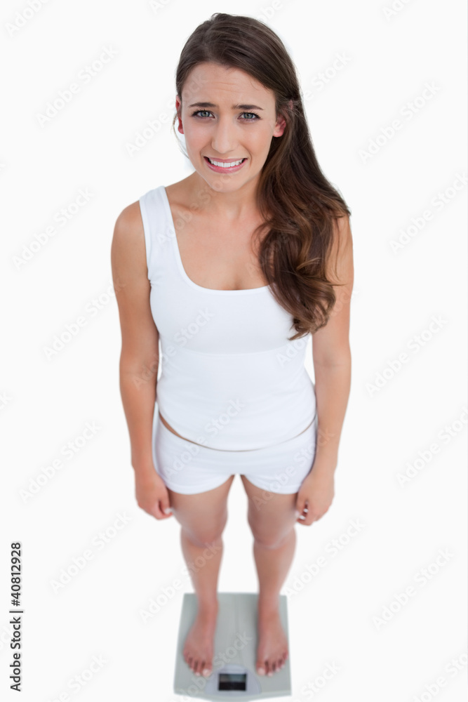 Sad brunette woman weighing herself Sad brunette woman weighing herself