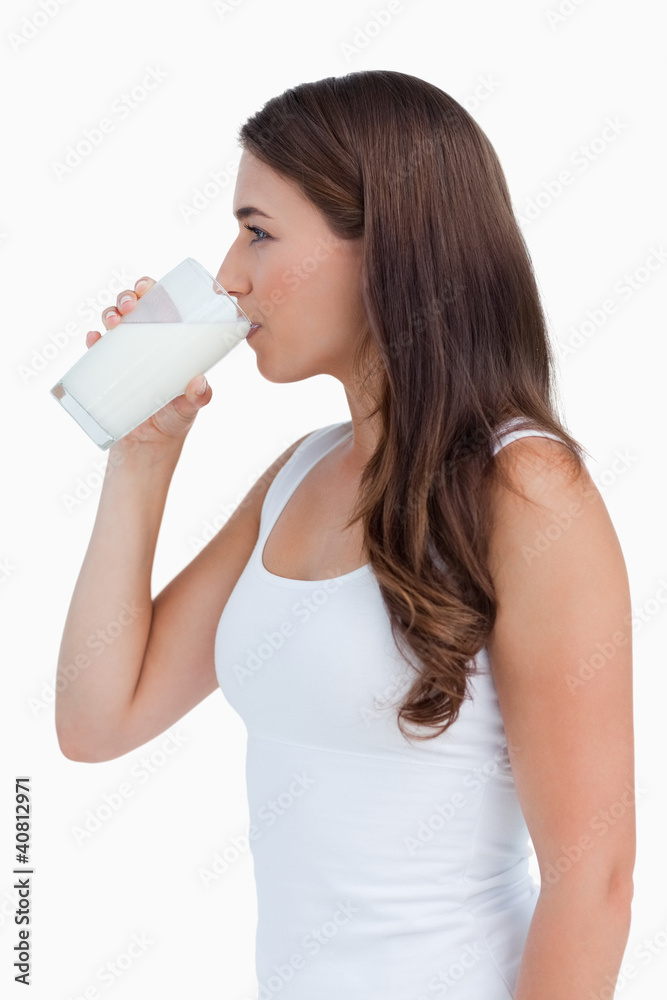 Side view of a young woman drinking a glass of milk Side view of a young woman drinking a glass of milk