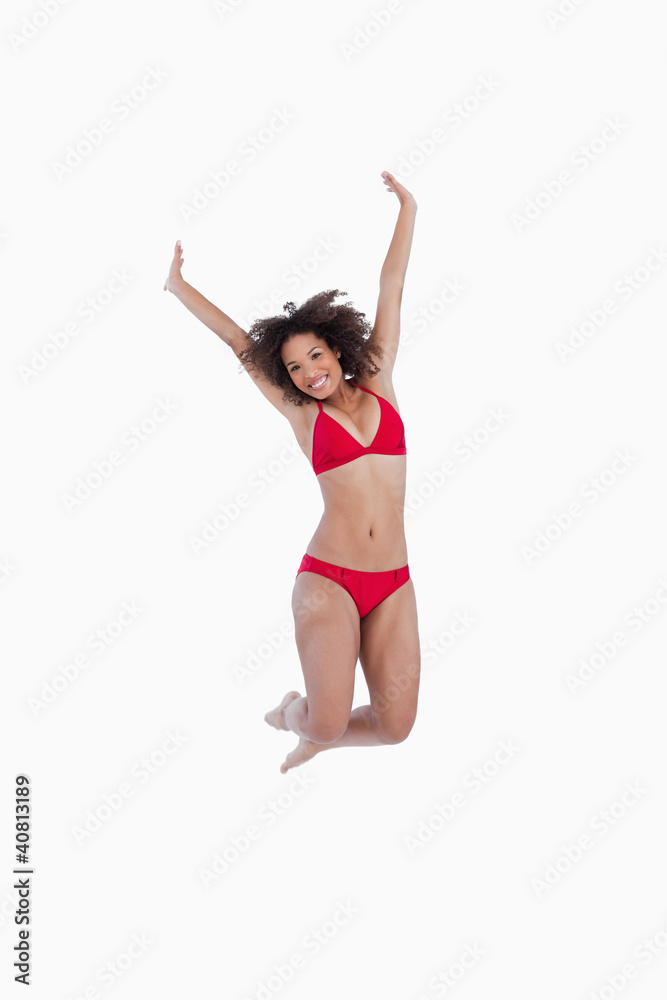 Smiling brunette jumping while raising her arms
