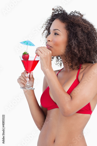 Young brunette looking away while sipping a cocktail