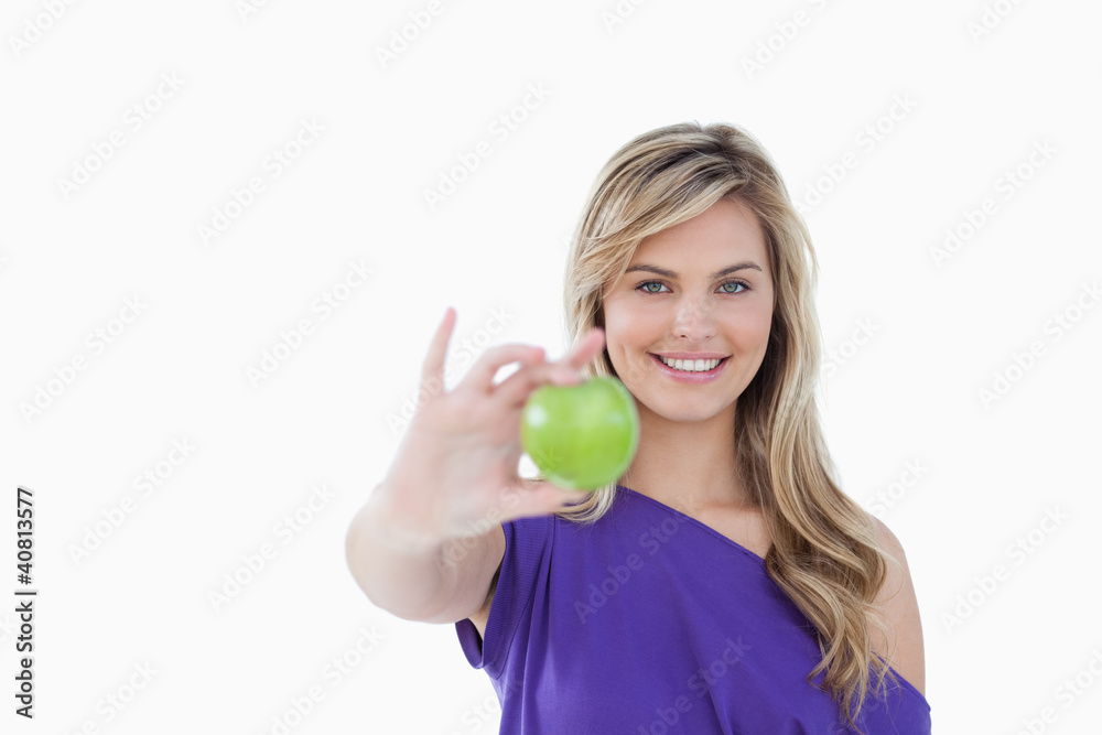 Smiling blonde woman holding a delicious green apple Smiling blonde woman holding a delicious green apple