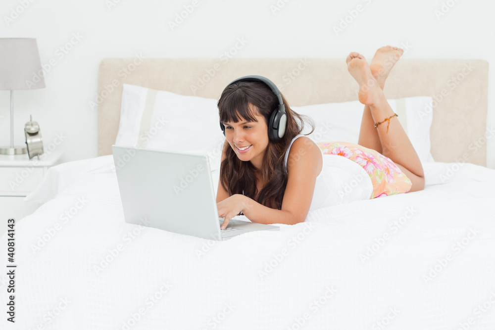 Young woman chatting on a laptop with earphones Young woman chatting on a laptop with earphones
