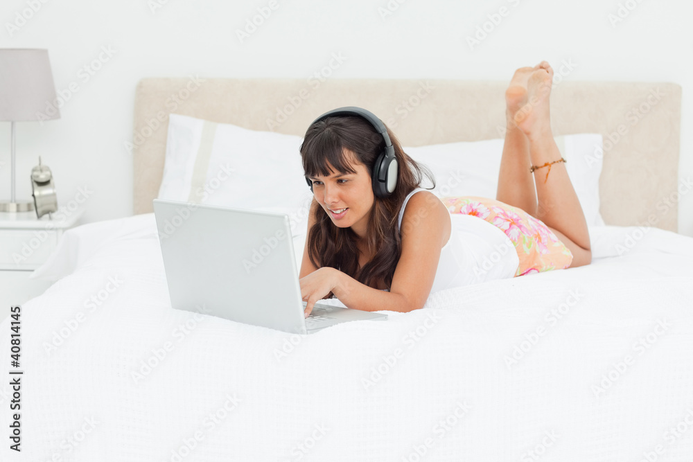 Young woman chatting with a laptop with earphones Young woman chatting with a laptop with earphones