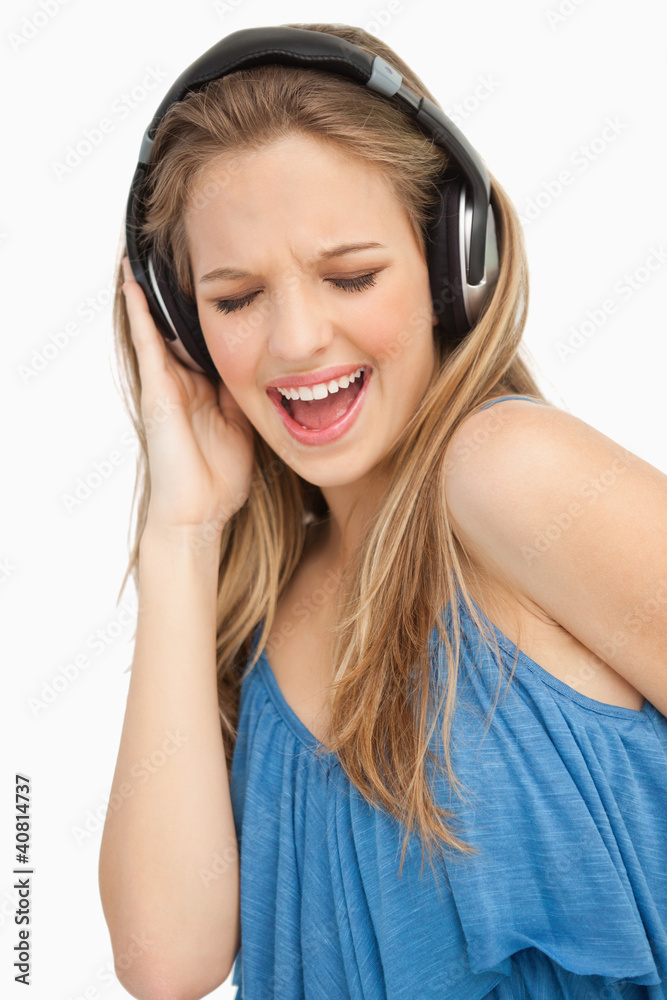 Close-up of a beautiful young woman singing while listening to m Close-up of a beautiful young woman singing while listening to m
