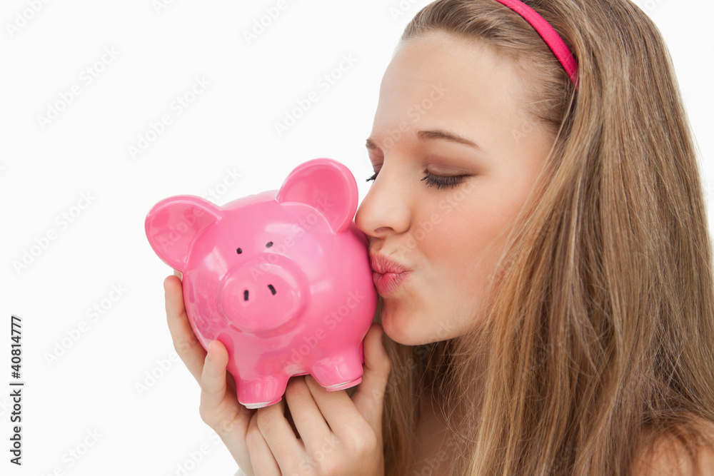 Close-up of a young woman kissing a piggy-bank Close-up of a young woman kissing a piggy-bank