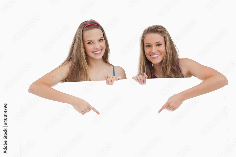 Portrait of young women holding and pointing a blank sign Portrait of young women holding and pointing a blank sign