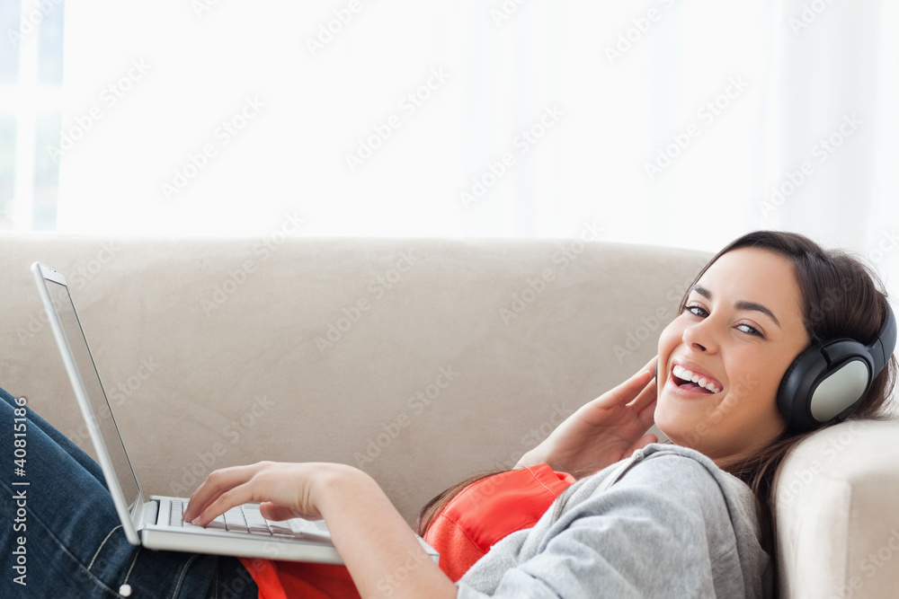 Laughing woman ying on the couch while looking at the camera Laughing woman ying on the couch while looking at the camera
