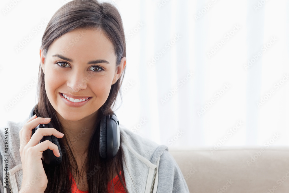 A brightly smiling woman holding headphones as she looks into th A brightly smiling woman holding headphones as she looks into th