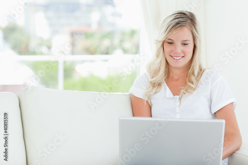 A woman smiling as she looks at the screen of a laptop