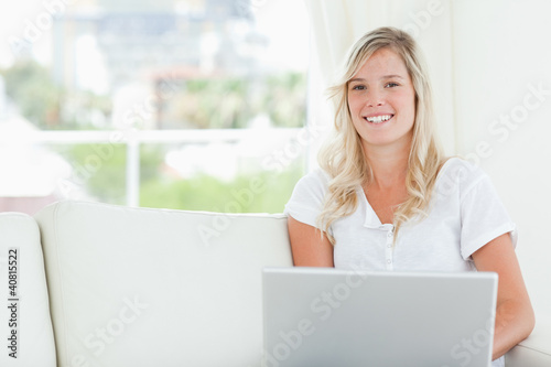 A smiling woman holding a laptop as she looks at the camera © WavebreakmediaMicro