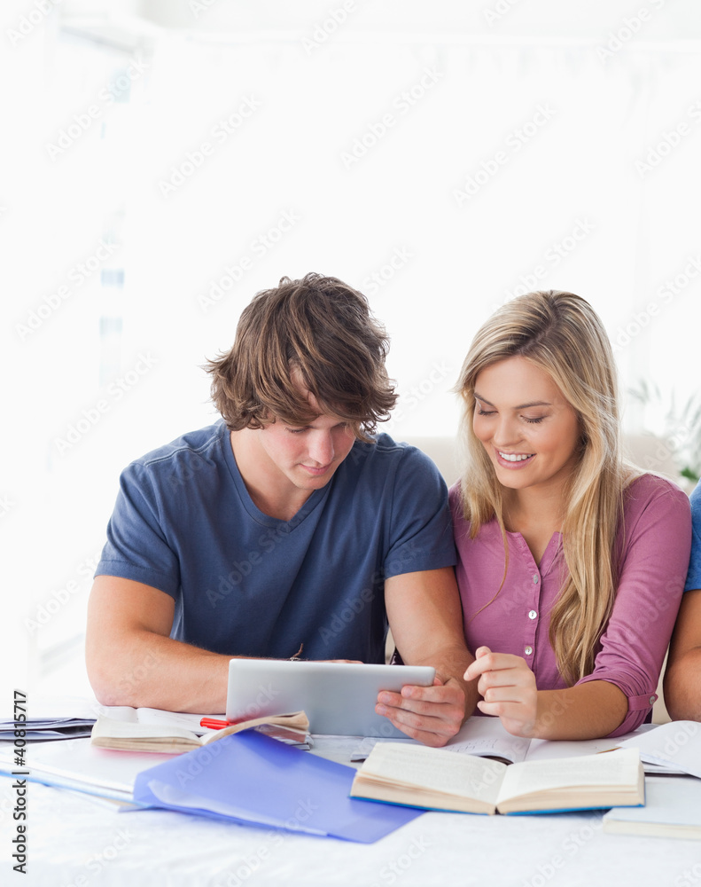 A couple look at a tablet together while smiling A couple look at a tablet together while smiling