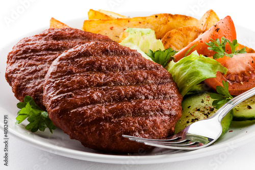 Grilled beefsteaks, baked potatoes and vegetable salad
