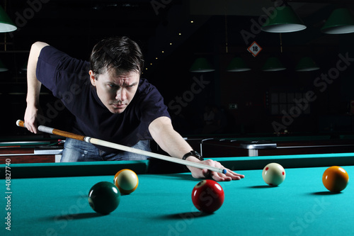 Man learning to play snooker in the dark club.