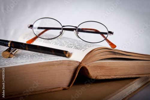 Glasses and pen laying on an old book