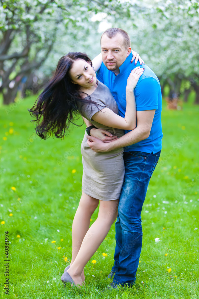 Fototapeta premium Young Couple in love in the spring blossoming apple orchard
