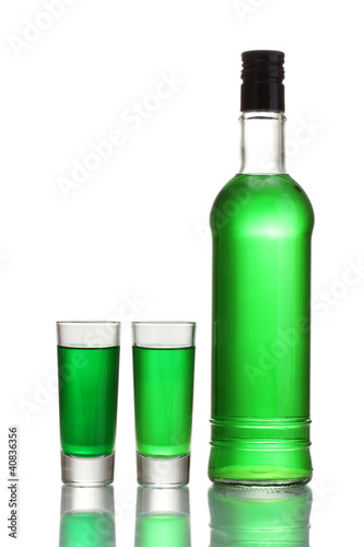 bottle and two glasses of absinthe isolated on white