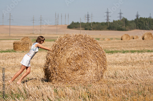 Obraz na plátne Girl is pushing on the roud haystack
